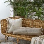 Wicker sofa with decorative pillows and plants in a room.