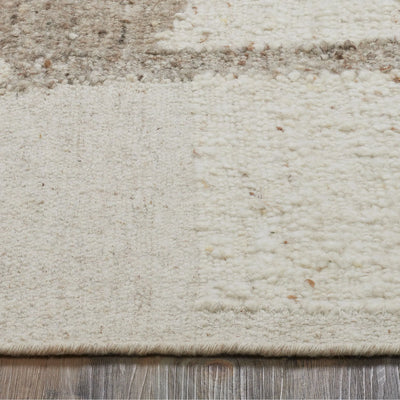 Close-up of a textured beige rug with subtle patterns on a wooden floor.