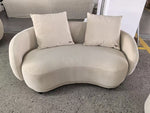 Beige wavy sofa with two cushions on a concrete floor.