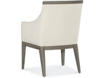 A beige upholstered dining chair with armrests and wooden legs, viewed from a front angle.