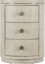 A beige round nightstand with three drawers and circular knobs on each drawer.