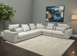 Gray sectional sofa in a living room with a abstract painting on the wall.