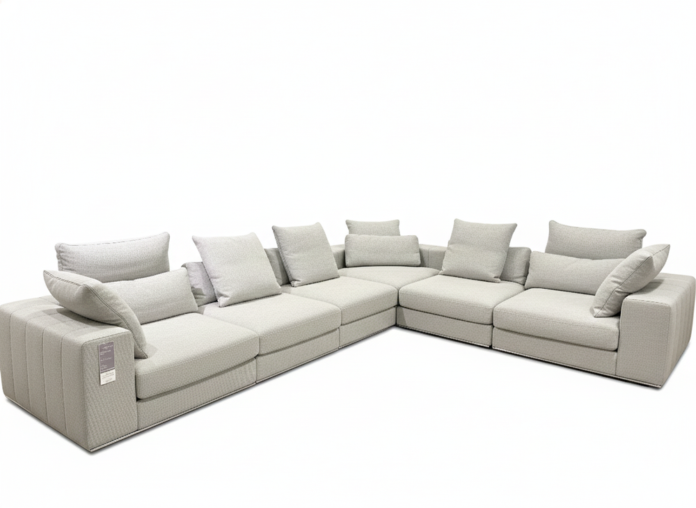 Gray sectional sofa with multiple cushions on a white background