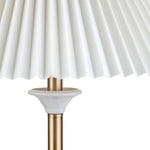 Close-up of a lamp with a white pleated shade and gold base on a white background