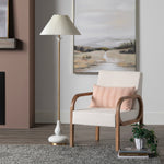 Modern living room with a cream armchair, floor lamp, and artwork on the wall.