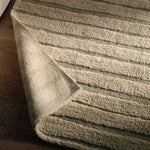 Textured green rug on a wooden floor