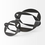 A round, black metal decorative object with a geometric design.