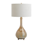 A table lamp with a tapered drum shade in off-white fabric, a metallic gold stem, and a pear-shaped glass base in a warm champagne-gold tone with subtle light blue floral detailing near the bottom, set against a plain white background.