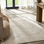 Beige area rug with geometric pattern in a room with a couch and table.