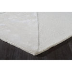 Close-up of a textured white rug corner on a dark surface