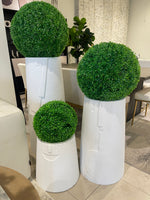 A set of three white, textured, rounded planters of different sizes, each containing a spherical artificial green plant.