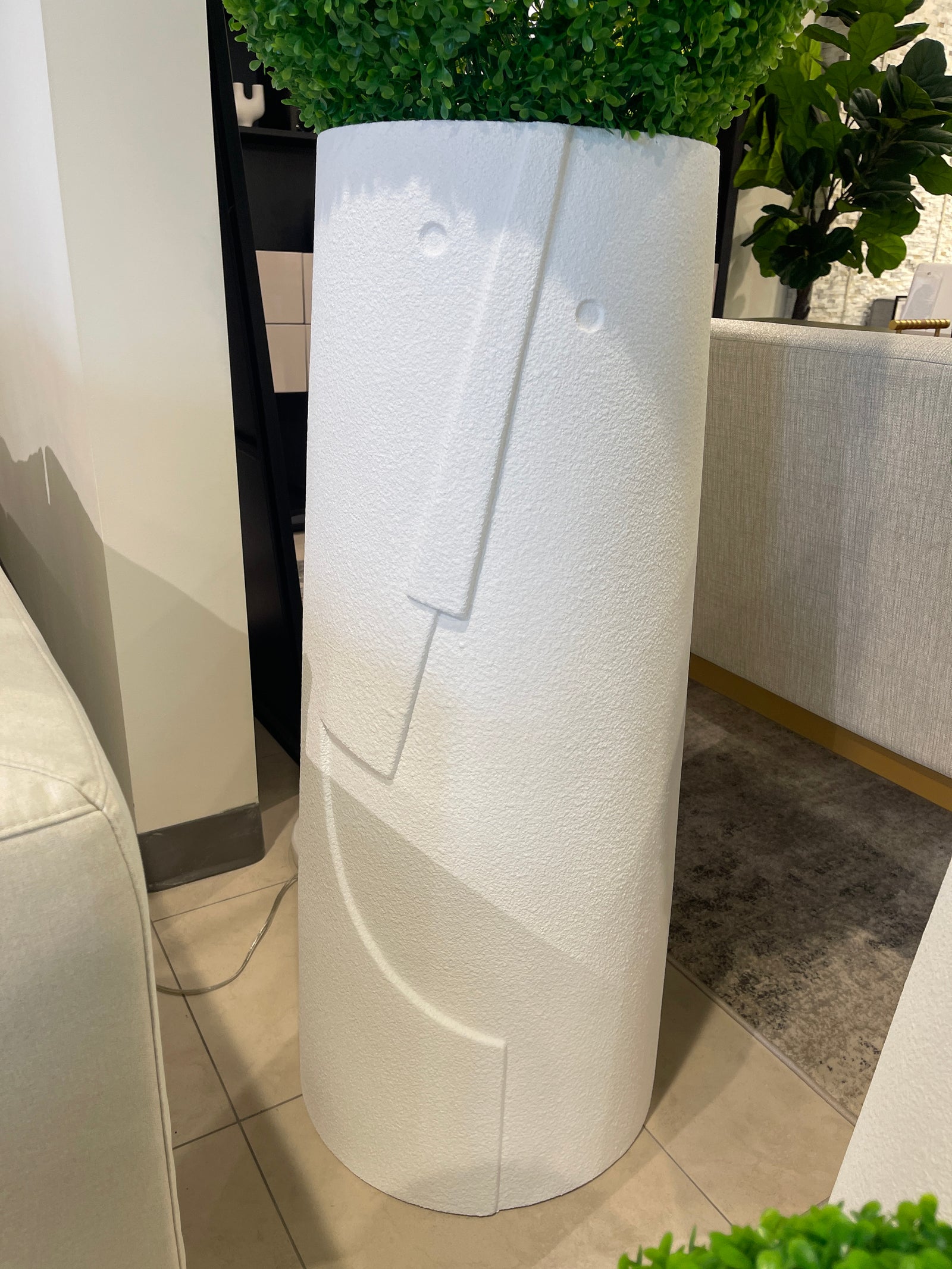 A white, textured, rounded planters of different sizes, each containing a spherical artificial green plant.