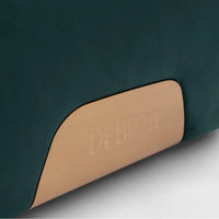 Close-up of a green cushion with a tan label displaying 'DEBRAH' on a dark background.