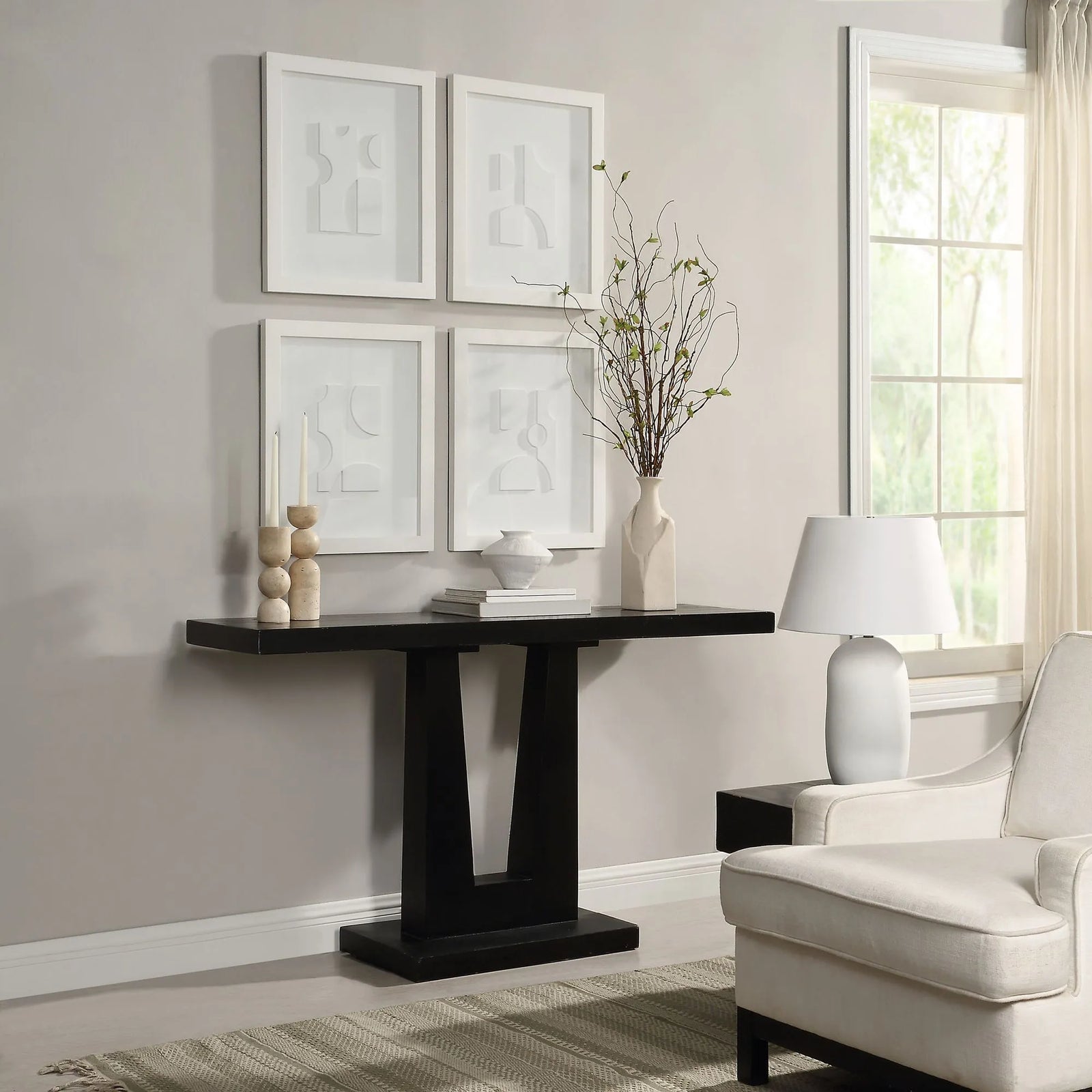Modern living room with a black console table, white armchair, and framed abstract art on the wall.