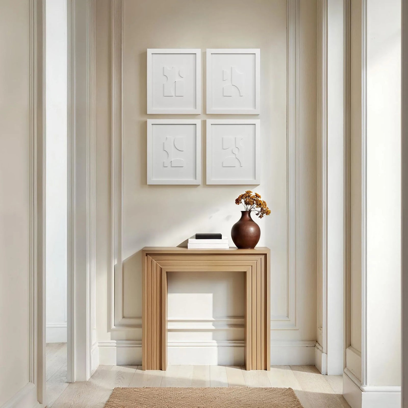 Wooden console table with a vase and books against a wall with framed art