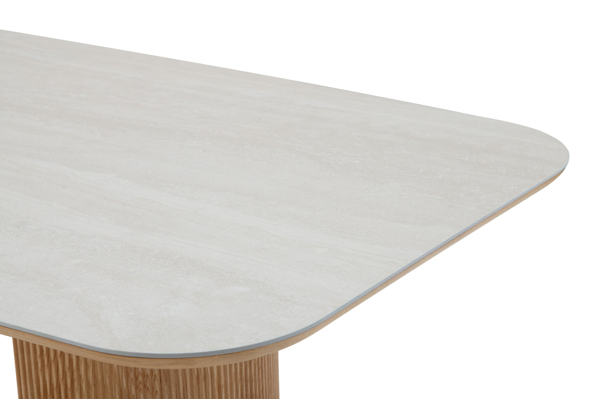 Close-up of a modern dining table with a light gray surface and wooden base.