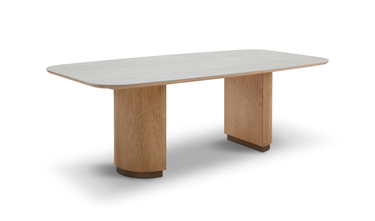 Modern dining table with light wood legs and a white top on a white background