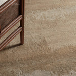 Close-up of a textured beige carpet with a wicker chair corner.
