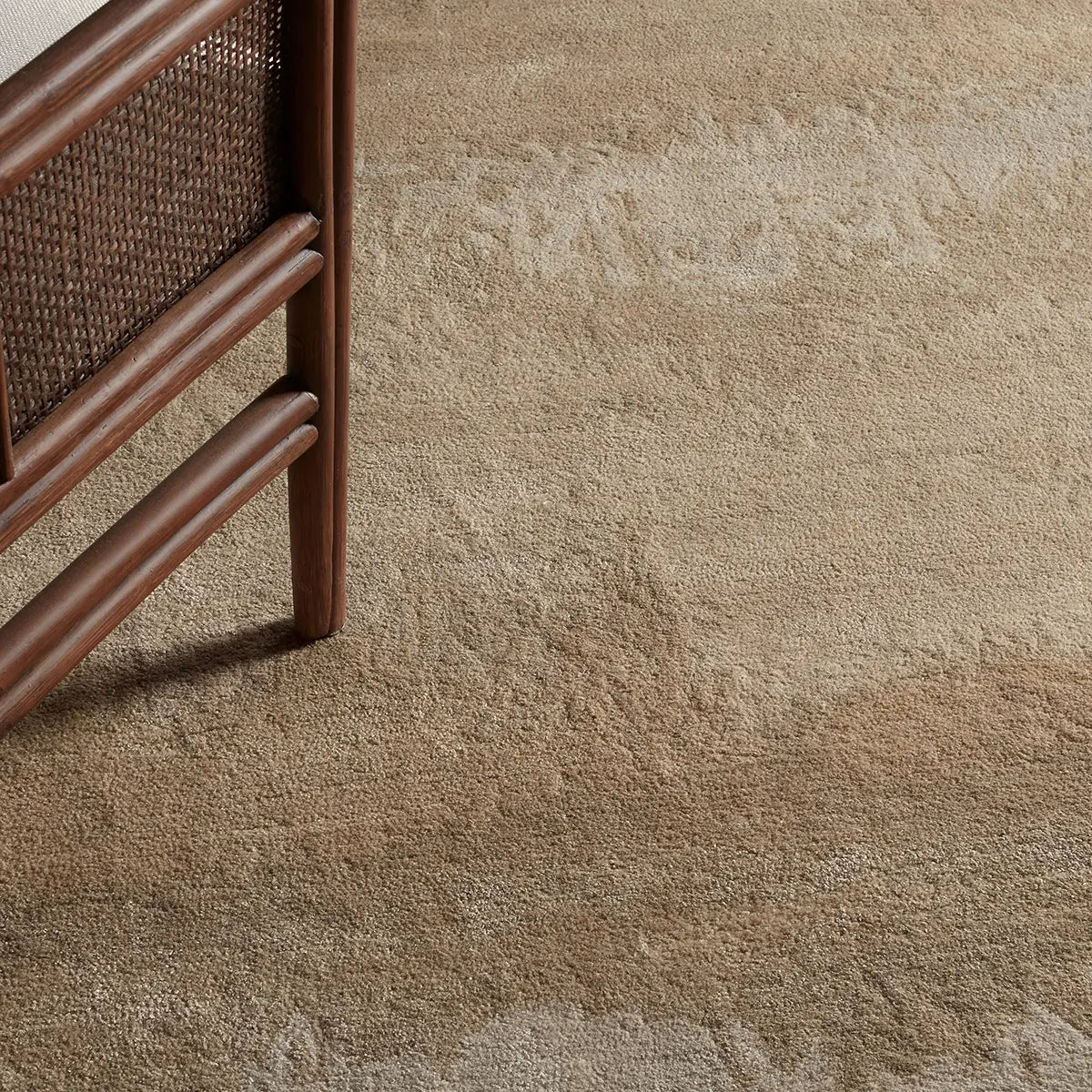 Close-up of a textured beige carpet with a wicker chair corner.