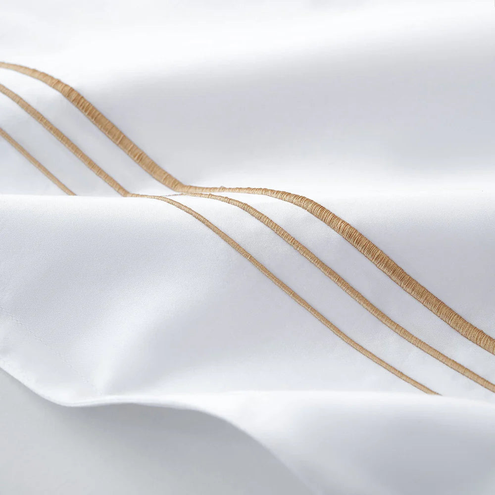 Close-up of white fabric with gold embroidery on a light gray background