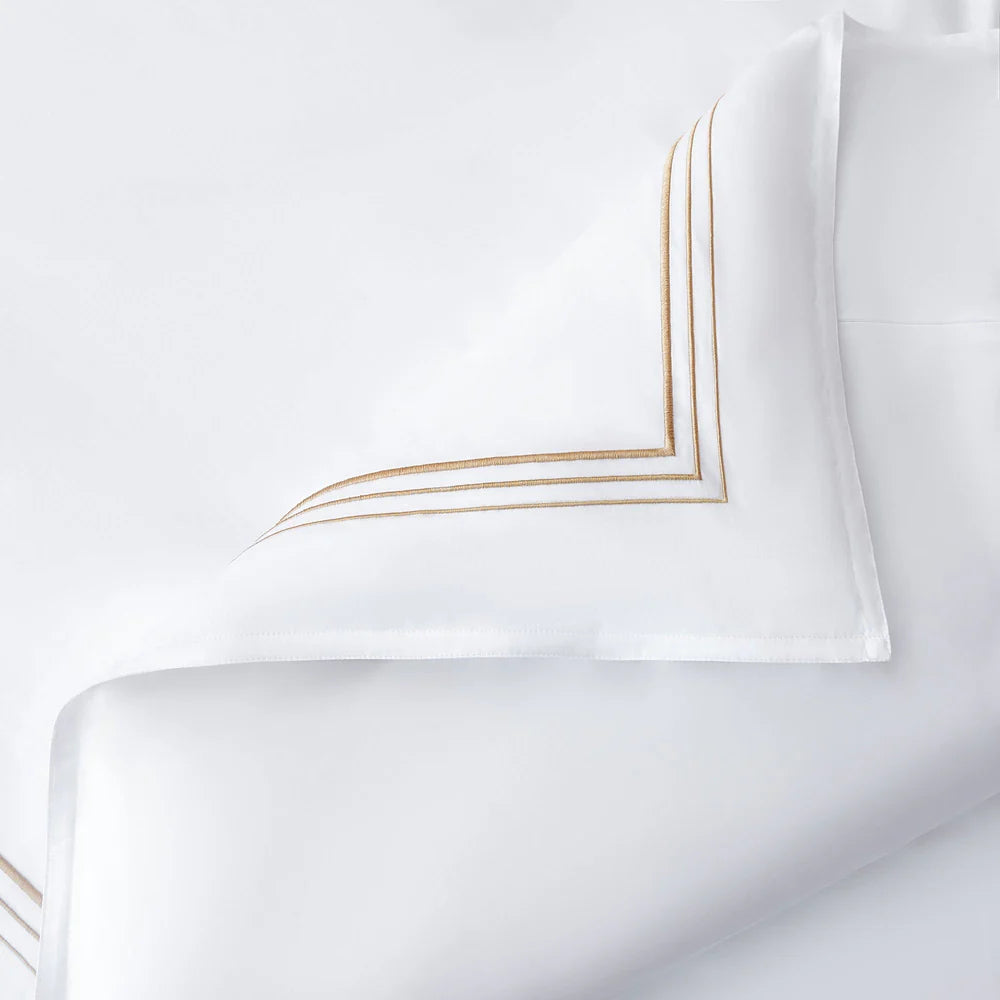 White pillowcases with gold embroidery on a white background