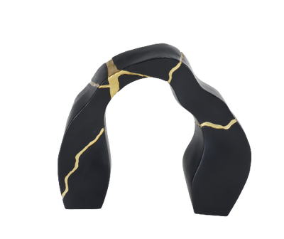 A black and gold statue decor object with a textured surface and a broken gold statue piece attached to the main body.