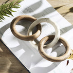 Three wooden rings on an open book with a plant in the background