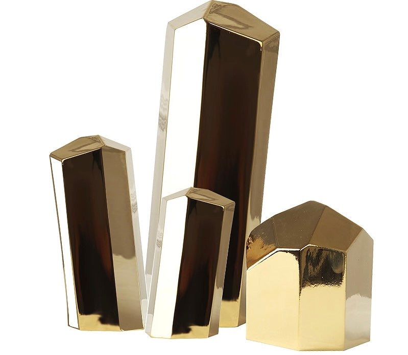 A set of brass decorative objects in different shapes, including a pyramid, a rectangle, and a triangular prism, with a shiny metallic finish.