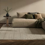 Beige sectional sofa with decorative pillows and a rug in a living room setting.