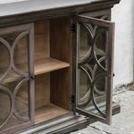 Wooden cabinet with decorative glass doors on a concrete surface.