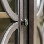 Close-up of a metal gate with circular design and a bolt.