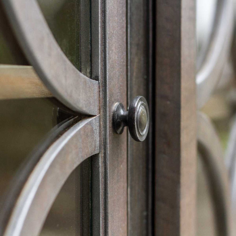 Close-up of a metal gate with circular design and a bolt.
