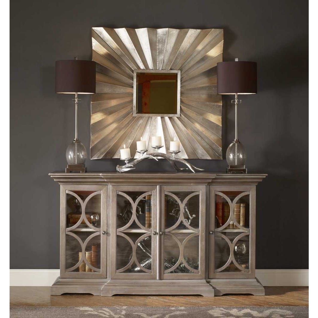 Decorative sideboard with a large mirror above it against a dark wall.
