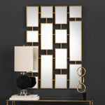 Decorative wall mirror with geometric design on a dark wall, accompanied by a lamp and sculptures.