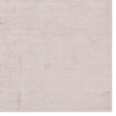 A beige area rug with a textured surface, power loomed construction, and a visible brand tag.
