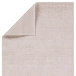 A beige area rug with a textured surface, power loomed construction, and a visible brand tag.