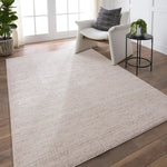 A beige area rug with a textured surface, power loomed construction, and a visible brand tag.