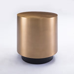 Gold cylindrical side table with black base on a white background