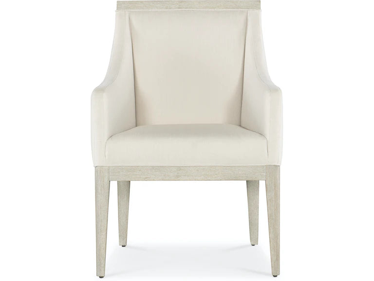 A beige upholstered dining chair with armrests and wooden legs, viewed from a front angle.