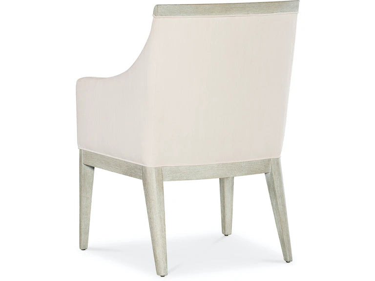 A beige upholstered dining chair with armrests and wooden legs, viewed from a front angle.