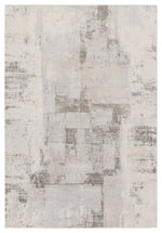 A white area rug with a geometric pattern featuring various shades of grey and a subtle wood floor appearance.