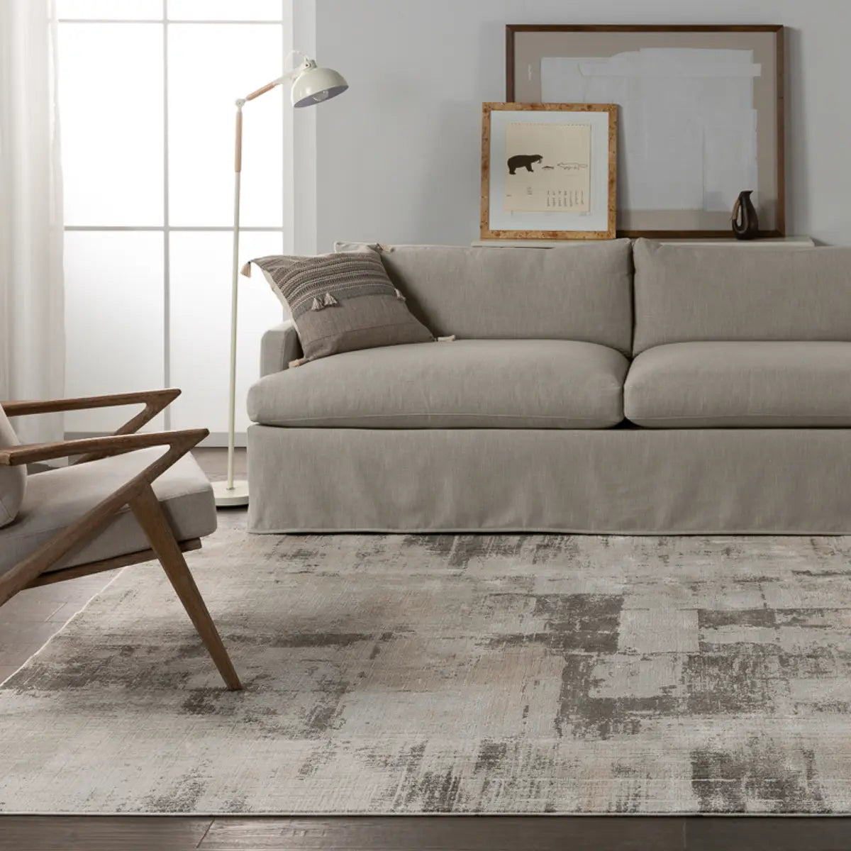 A white area rug with a geometric pattern featuring various shades of grey and a subtle wood floor appearance.
