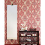 Decorative wall with pink and white patterned wallpaper, a mirror, and a wooden shelf with decorative items.