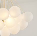 A contemporary silver metal chandelier with white glass shades, designed for indoor use.