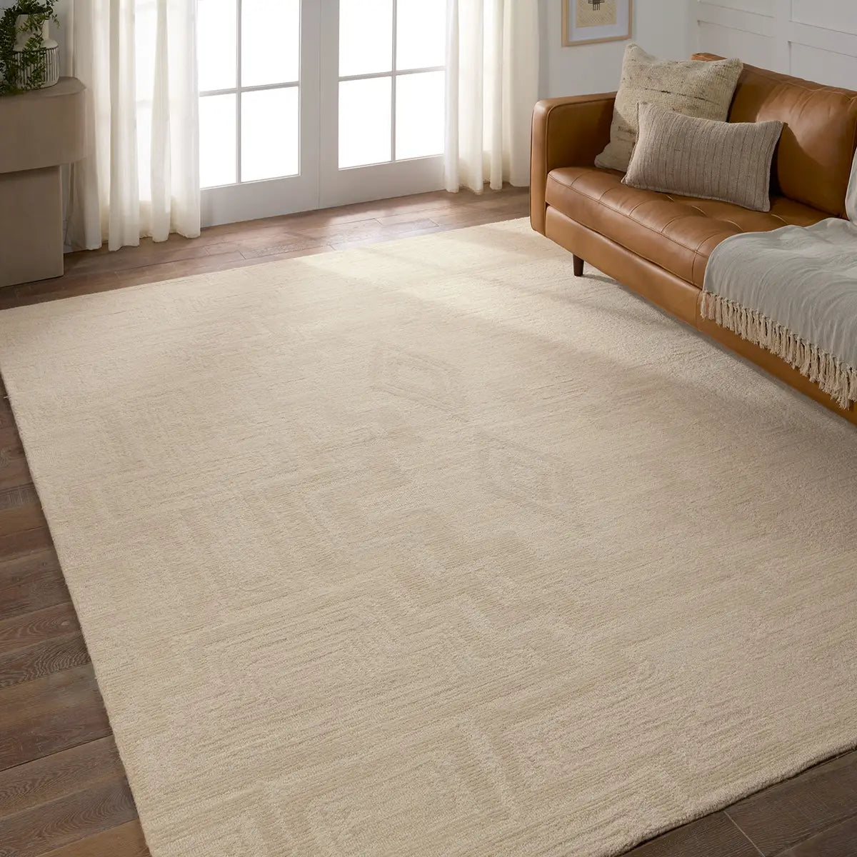 Beige rug in a living room with a brown sofa and large windows.