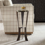 Modern side table with a glass of whiskey next to a plaid armchair in a living room setting.