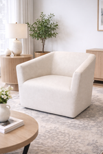White armchair in a living room setting with a lamp, plant, and coffee table.