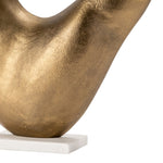 close-up of a gold-colored, curvilinear decorative artwork on a white base.