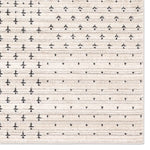Patterned rug with small black shapes on a beige background