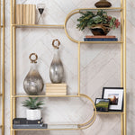 Gold shelving unit with decorative items against a white wall.
